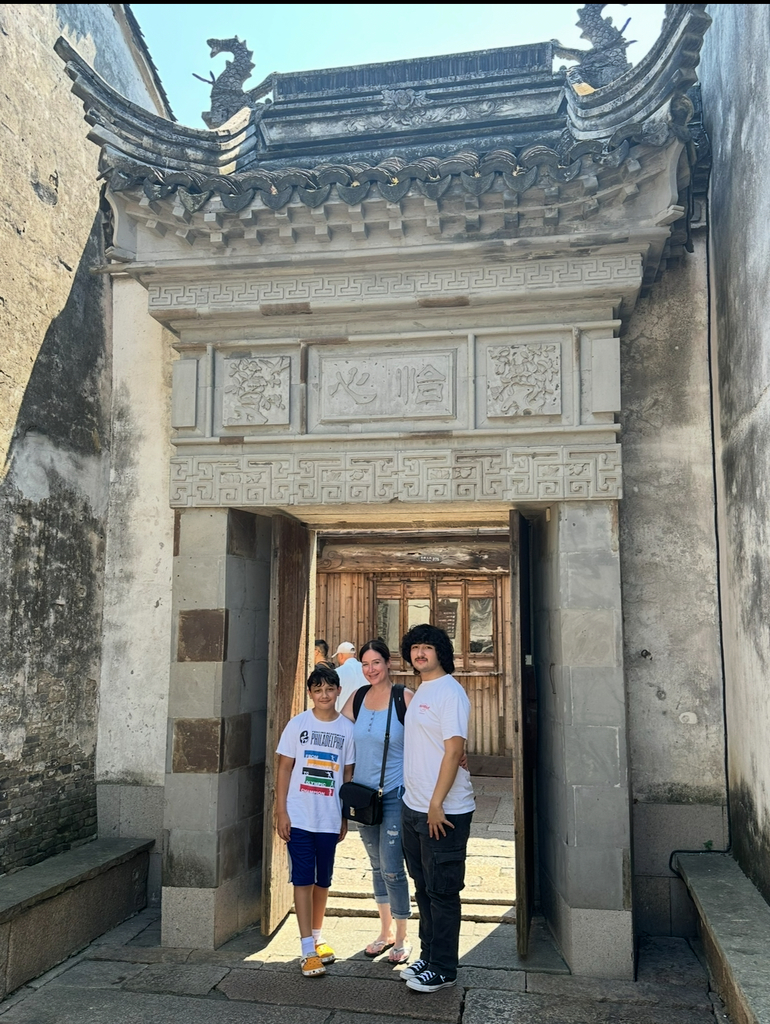Jonathan and Walter stand with their mom in a beautiful stone doorway in China