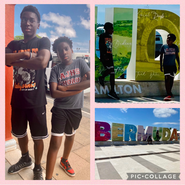 Josiah and Jordan stand together with arms crossed with blue skies behind them, and standing in front of huge huge colorful letters that spell out "BERMUDA"