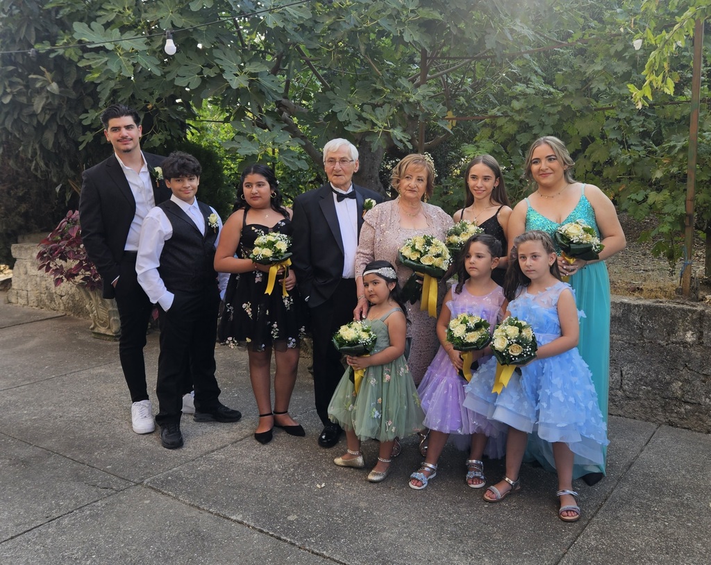 Pasquale and his family stand together at his grandparent's 50th wedding anniversary, wearing formal attire and holding floral bouquets
