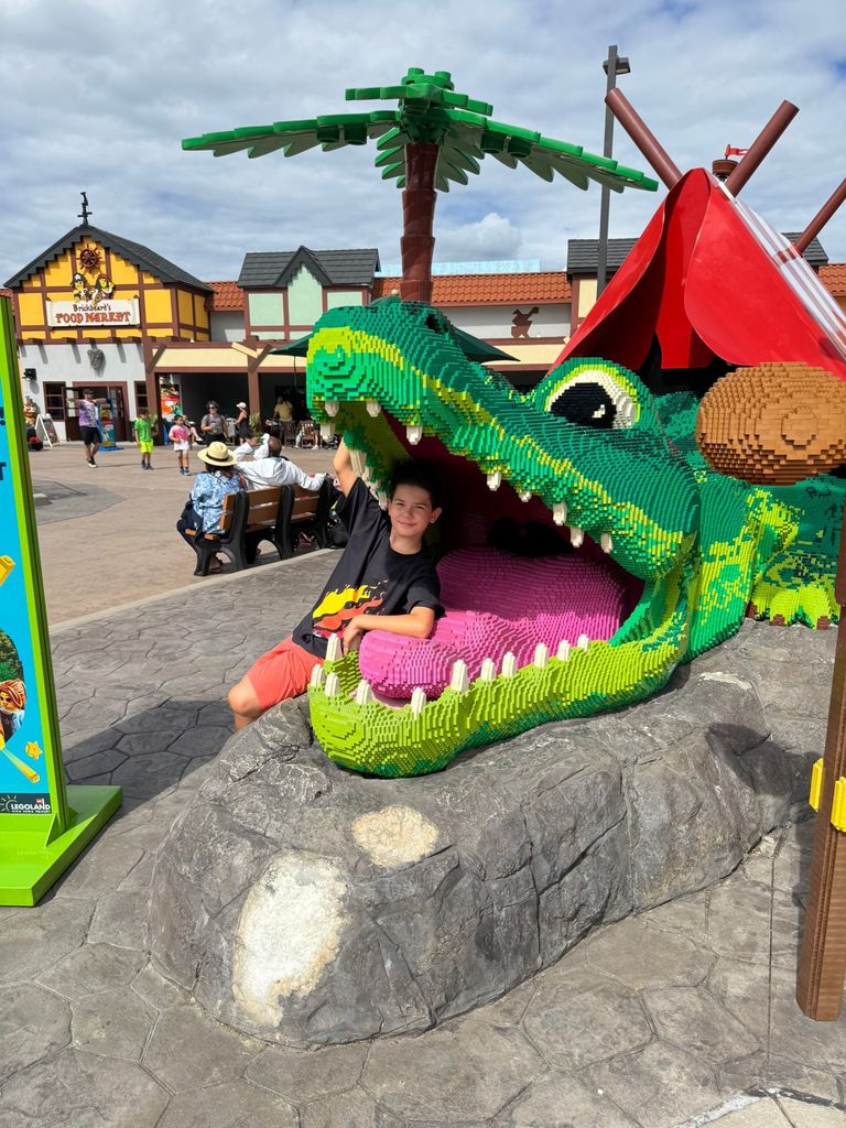 Andrii stis reasing inside of the open mough of a giant Lego crocodile