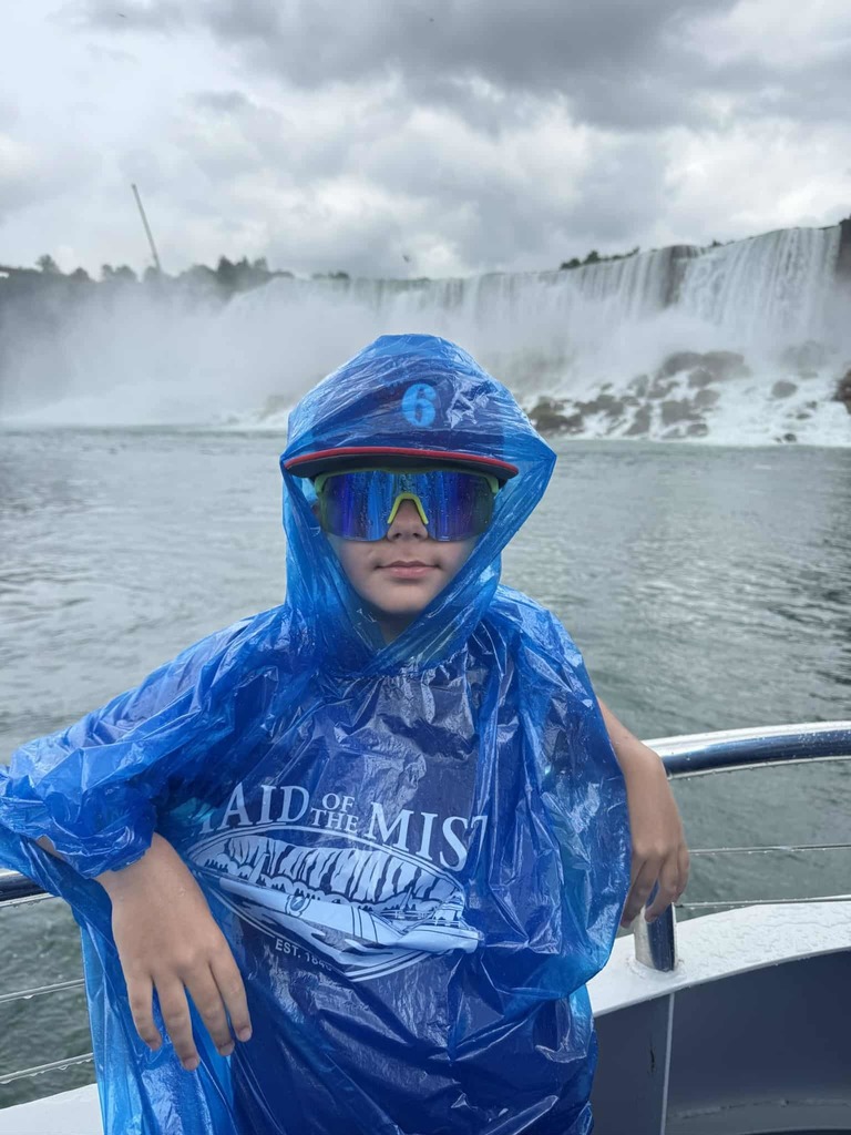 Andrii stands in front of the waterall at Niagara Falls, leaning on a railing