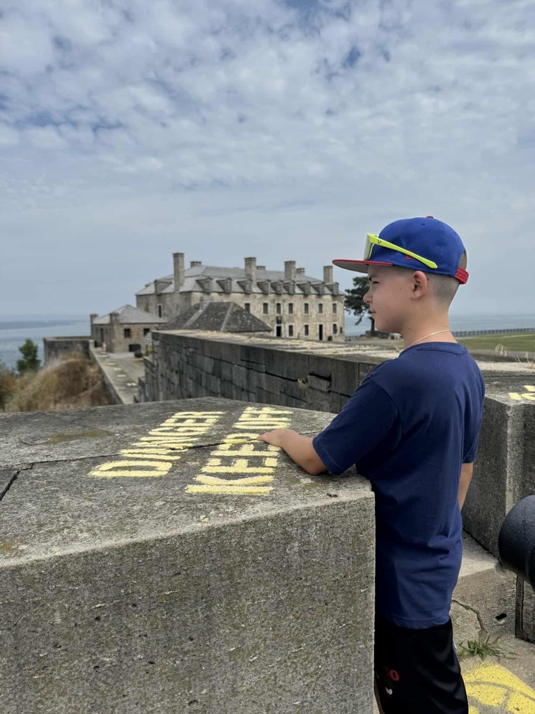 Andrii stands leaning on a stone wall with a castle-like stone building in the background