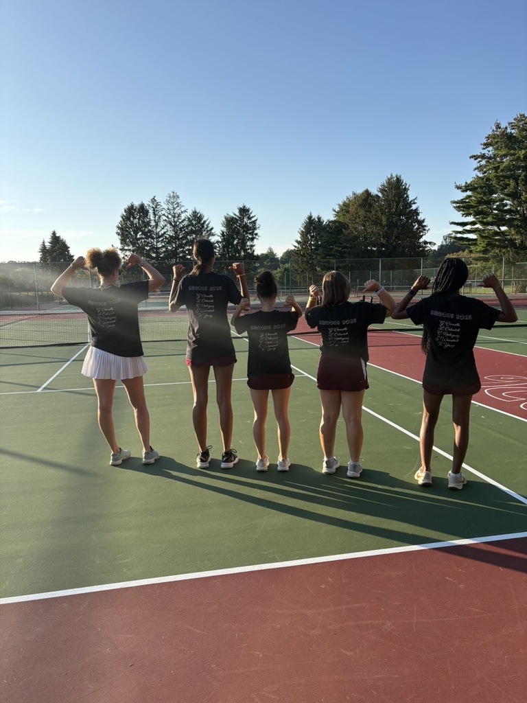 The coach and seniors posing showing the back of their shirts 
