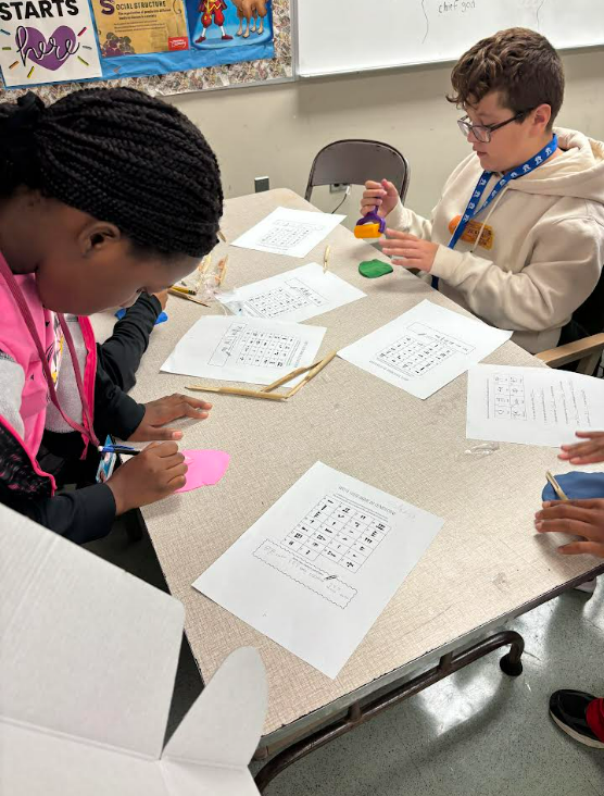 Image of 6th grade students writing their names using reeds and clay.