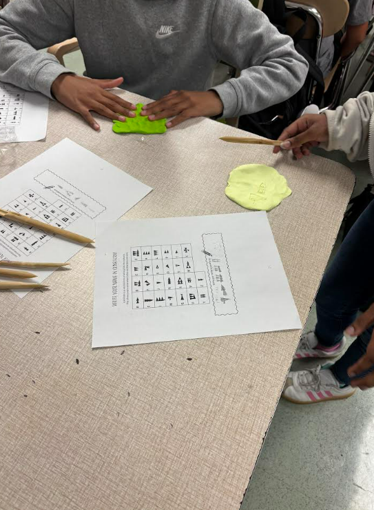 Image of 6th grade students writing their names using reeds and clay.