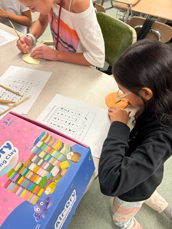 Image of 6th grade students writing their names using reeds and clay.