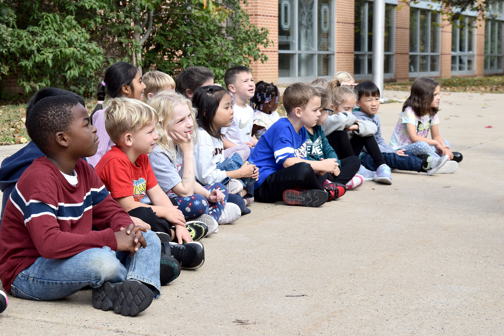 Overlook kindergarteners sit on the sidewalk and watch the firefighters' presentation