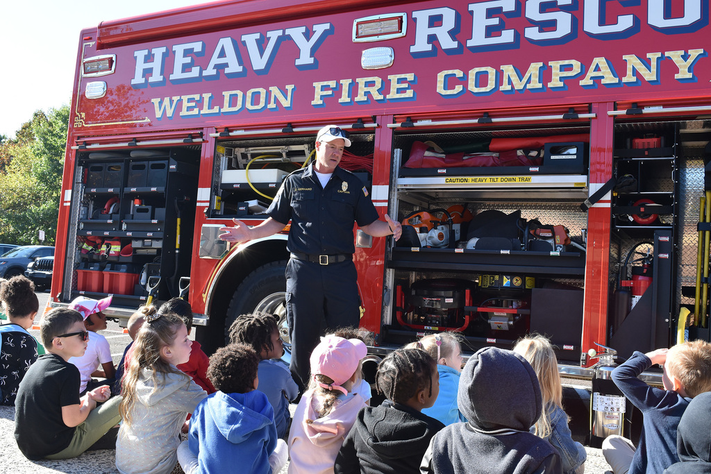 A firefighter stands in from of Weldon ire truck, speaking to kindergarteners at Copper Beech Elementary