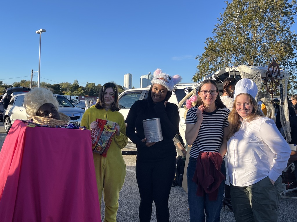 French Club students standing at Trunk or Treat in costume and holding candy to be distributed to attendees