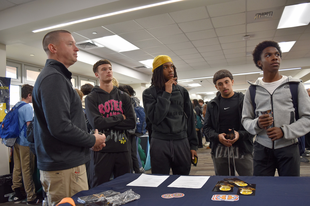 A union rep and students listen to another rep speaking, with literature on table before them