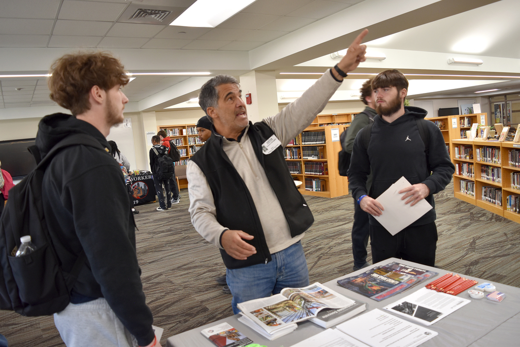 A union rep points to the ceiling while answering a question about his trade for a student