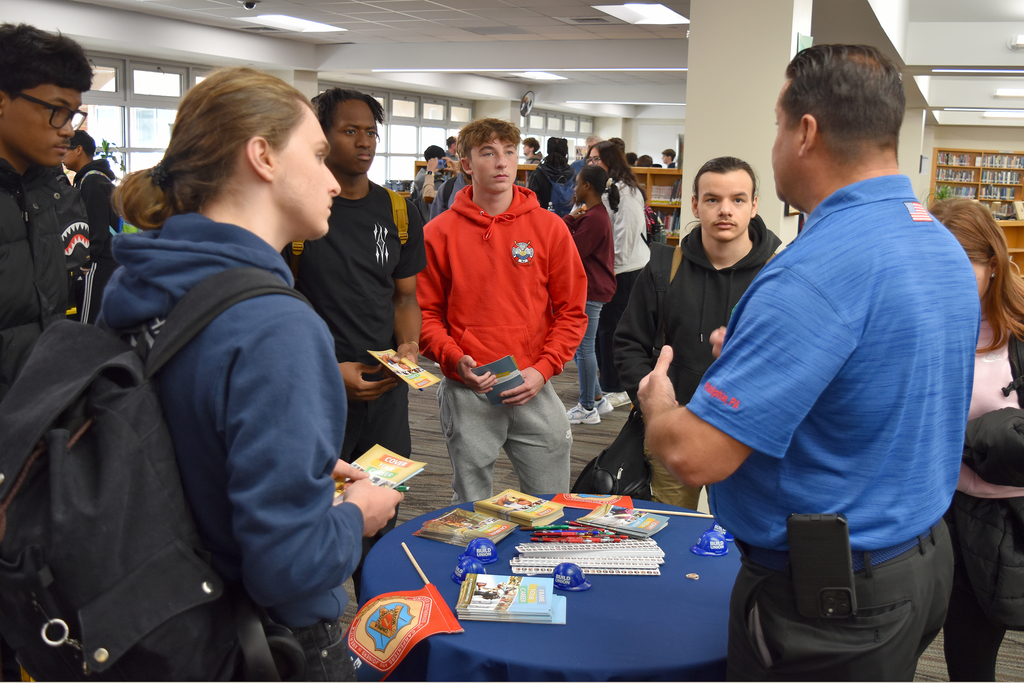 Students gather around a table of literature and listed to a union rep speak