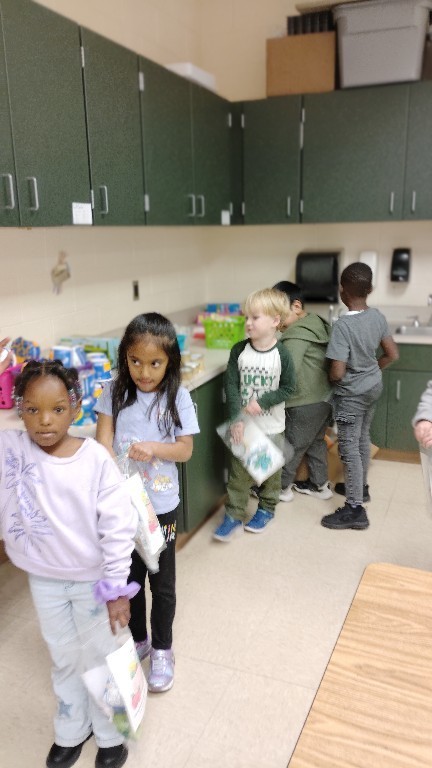 Overlook students move through a line of food items, filling their Belly Bags for those in need