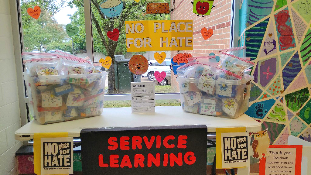 A Service Learning table with bins full of Belly Bags for those in need