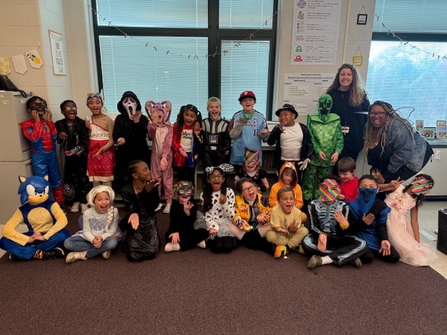 second graders smiling in their costumes on Halloween