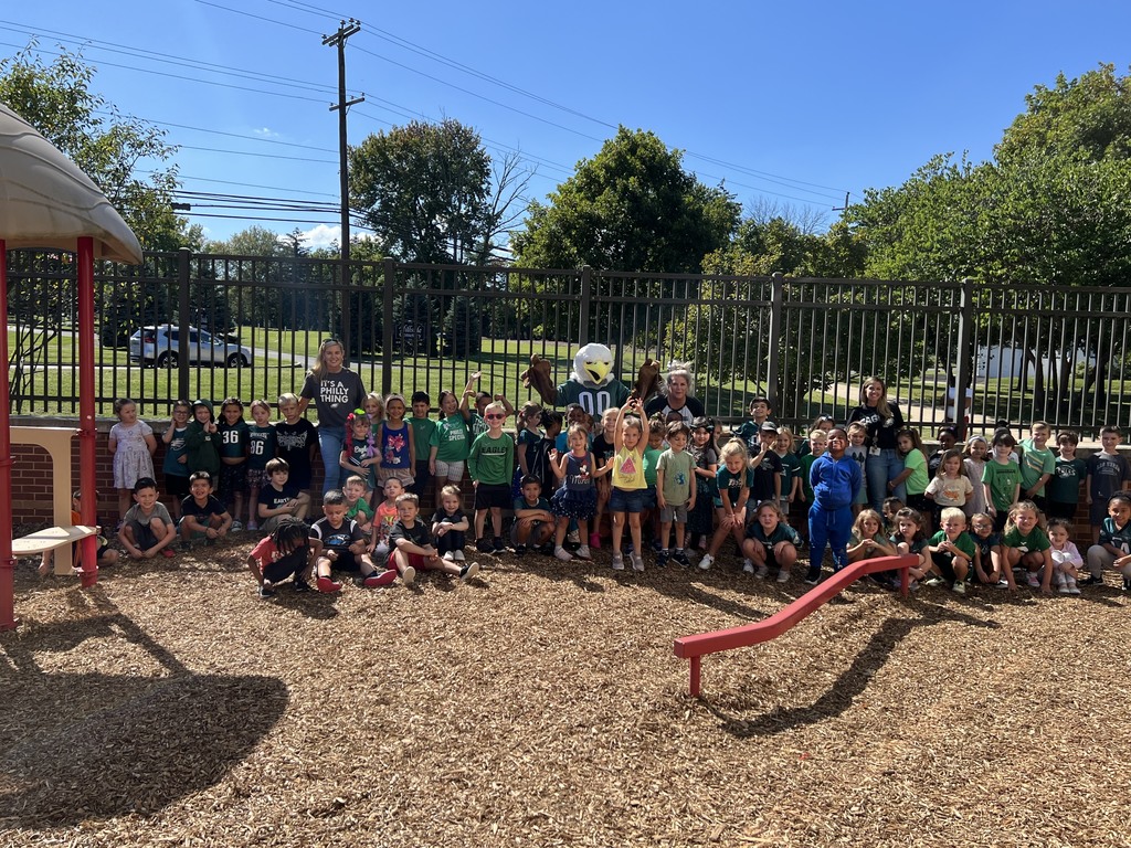 Swoop poses with kindergarteners on the playground