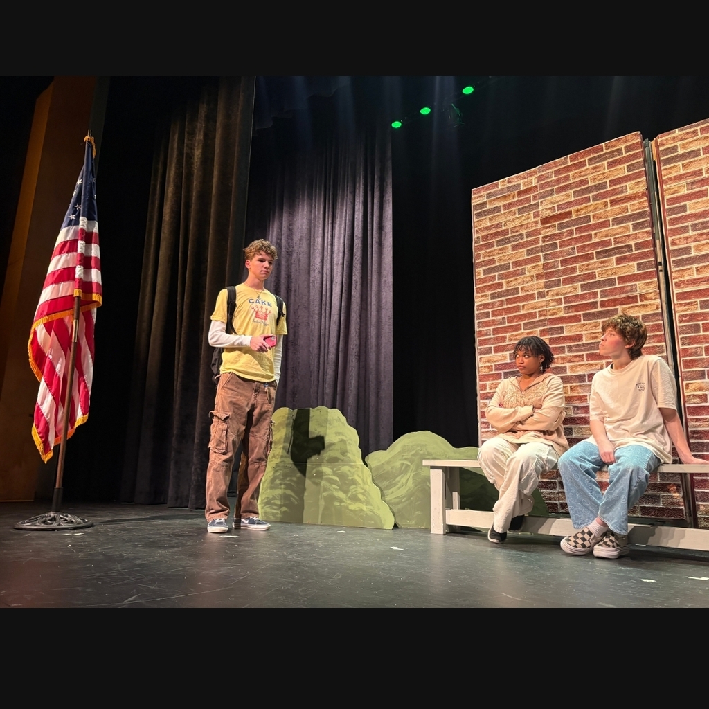 Actors on stage outside the school set