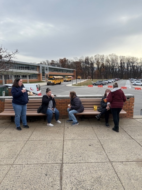 Transportation stit and enjoy their beverages with ASHS and buses in the background