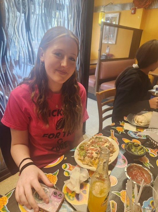 A female student smiles as she sits at her table enjoying her lunch in a Mexican restaurant