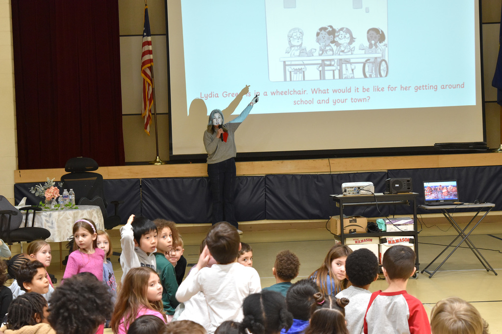 Ms. Wei Chase points to a slide to explain a theme of inclusion in one of her books