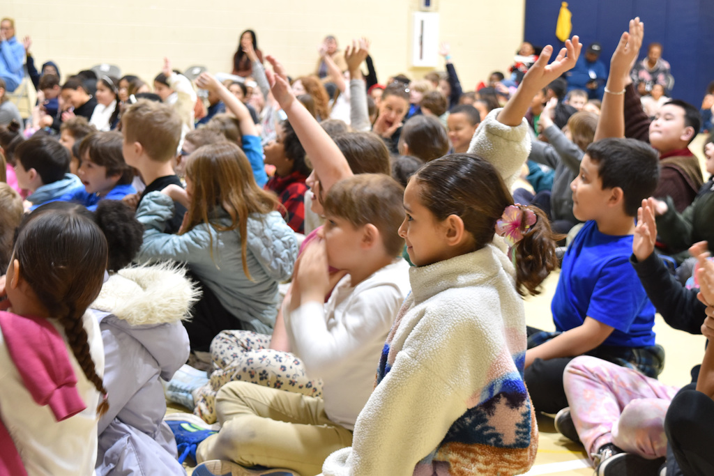 Roslyn students raise their hands to answer questions posed by Ms. Wei Chase