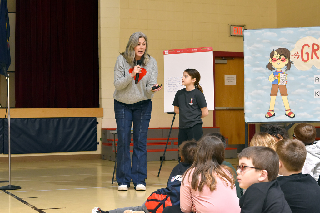 A student helps Ms. Mei Chase record student responses on a large writing tablet