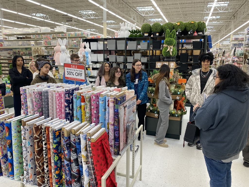 students stand in a line listening to Ms. Vanassche