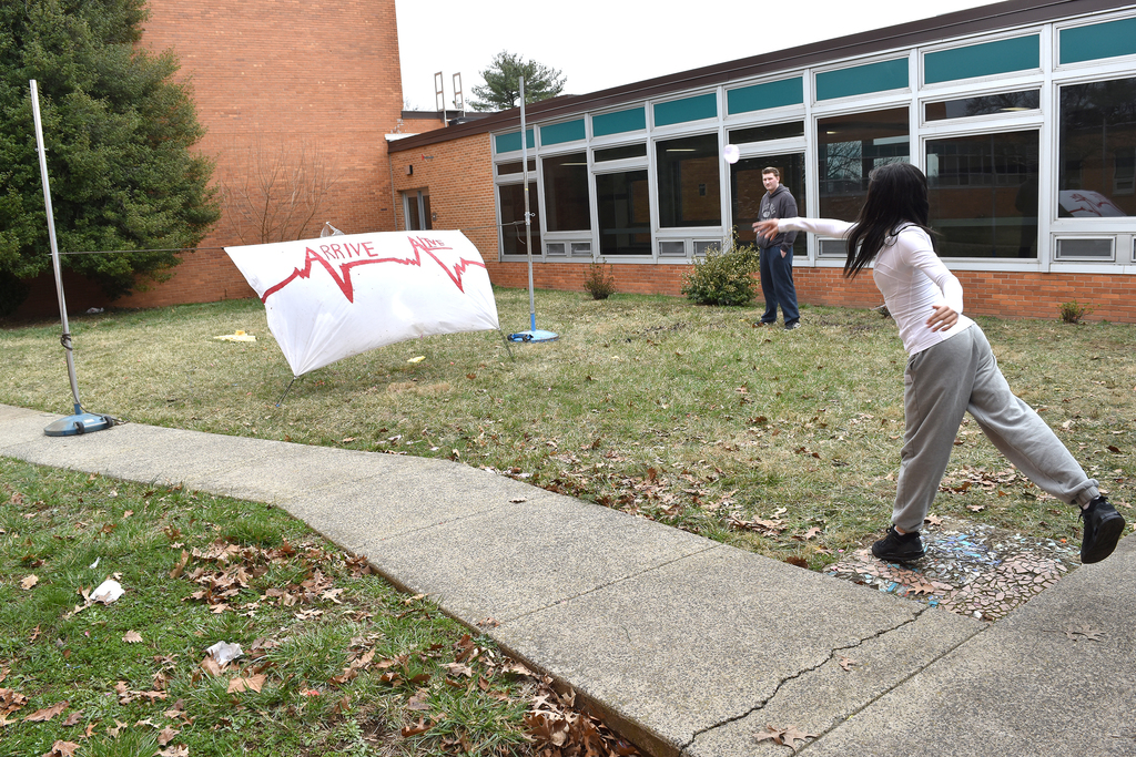 A senior throws a water baloon at a fabric backdrop to demonstrate the effects of a collision