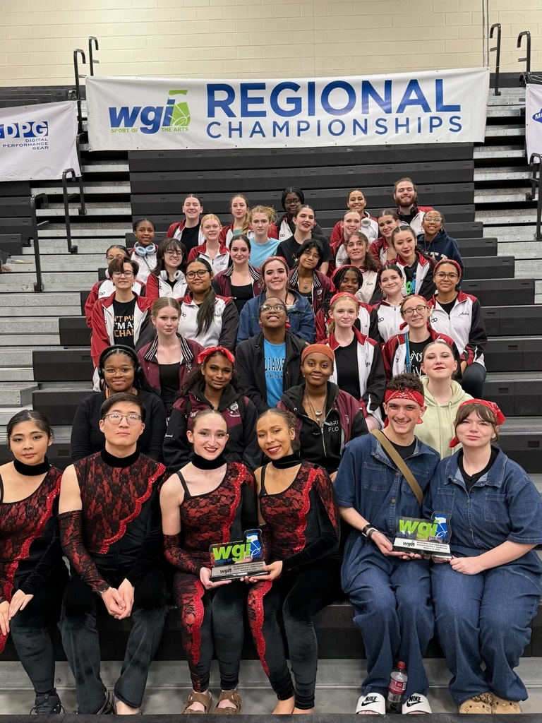 The entire ASHS colorguard taking a group photo in front of the WGI Regional Championship banner