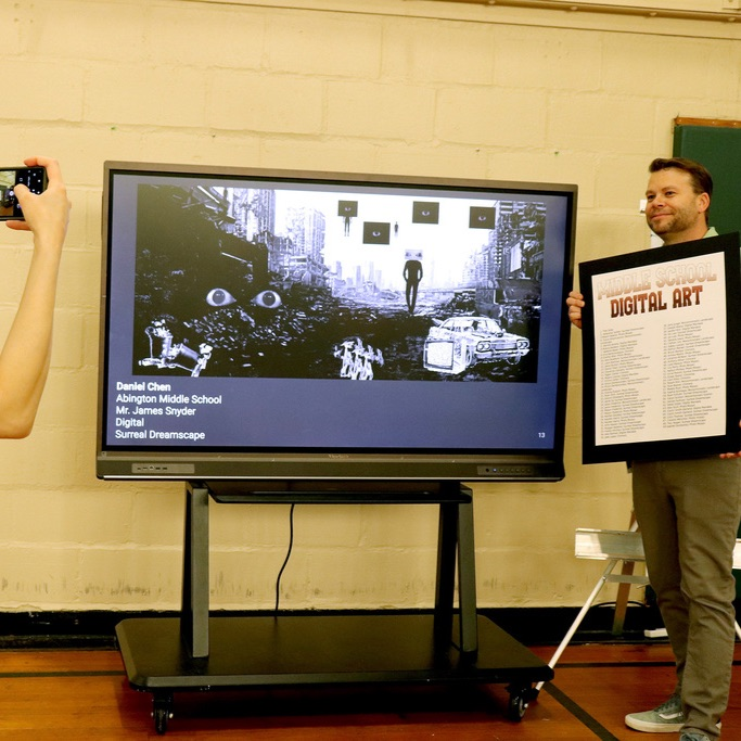Mr. Snyder stands before a screen showing a digital artwork submission