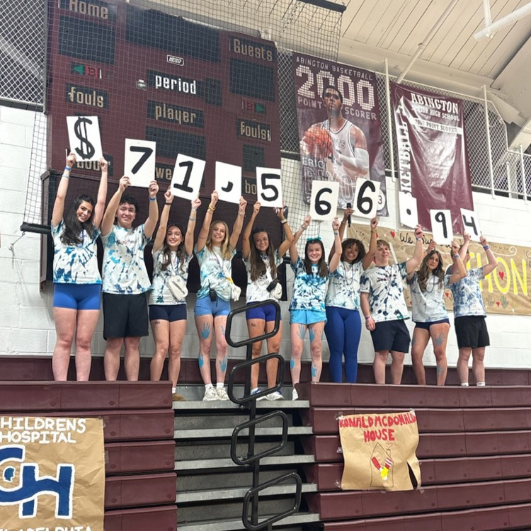 Students stand on bleachers holding up the numbers "71,566.94" to show the amount raised by AbingTHON