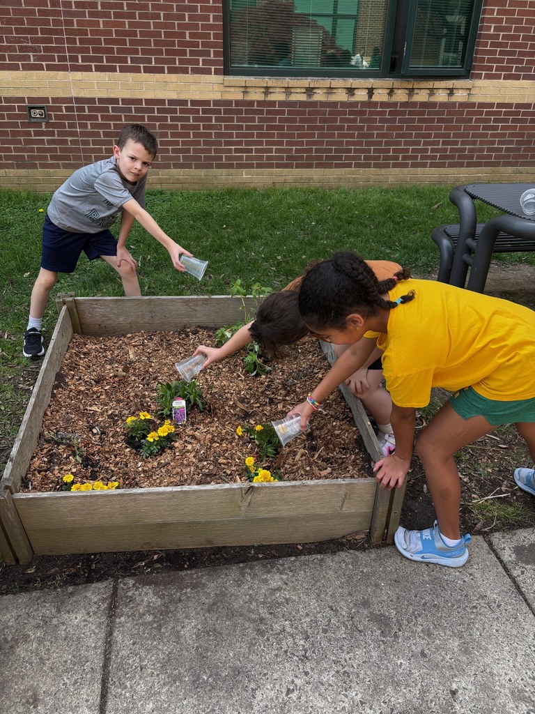 second graders watering the plants