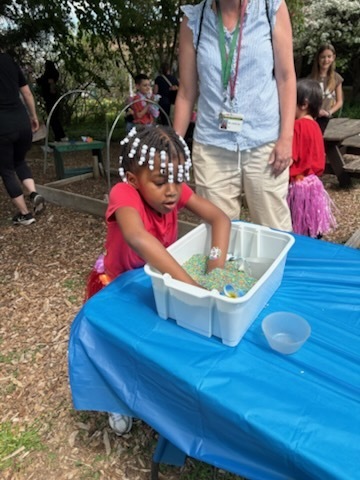 A student digs into a tray of beads looking for treasure at McKinley's Autism Awareness event