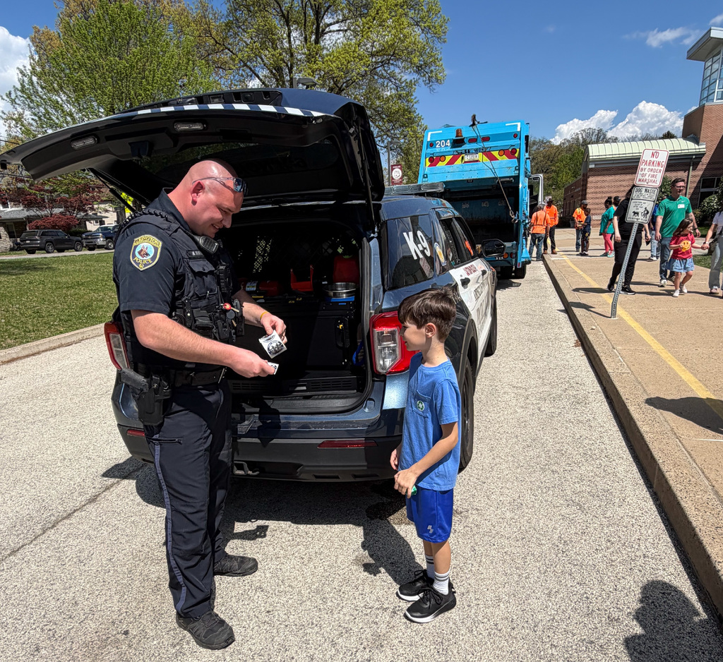 A police officer shares stickers with a student at Highland's Autism Awareness event.