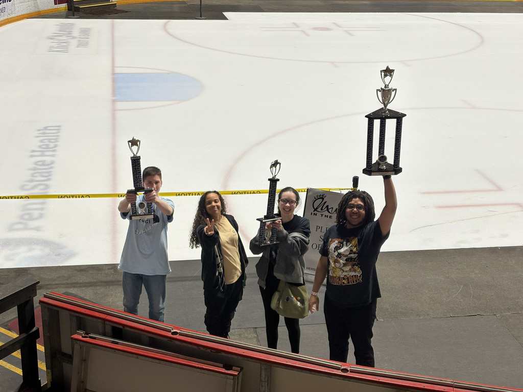 Four students hold up the trophies that they earned in the choral competition