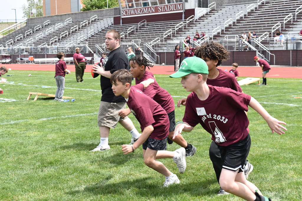 An ASHS student leads 5th graders in a game of football