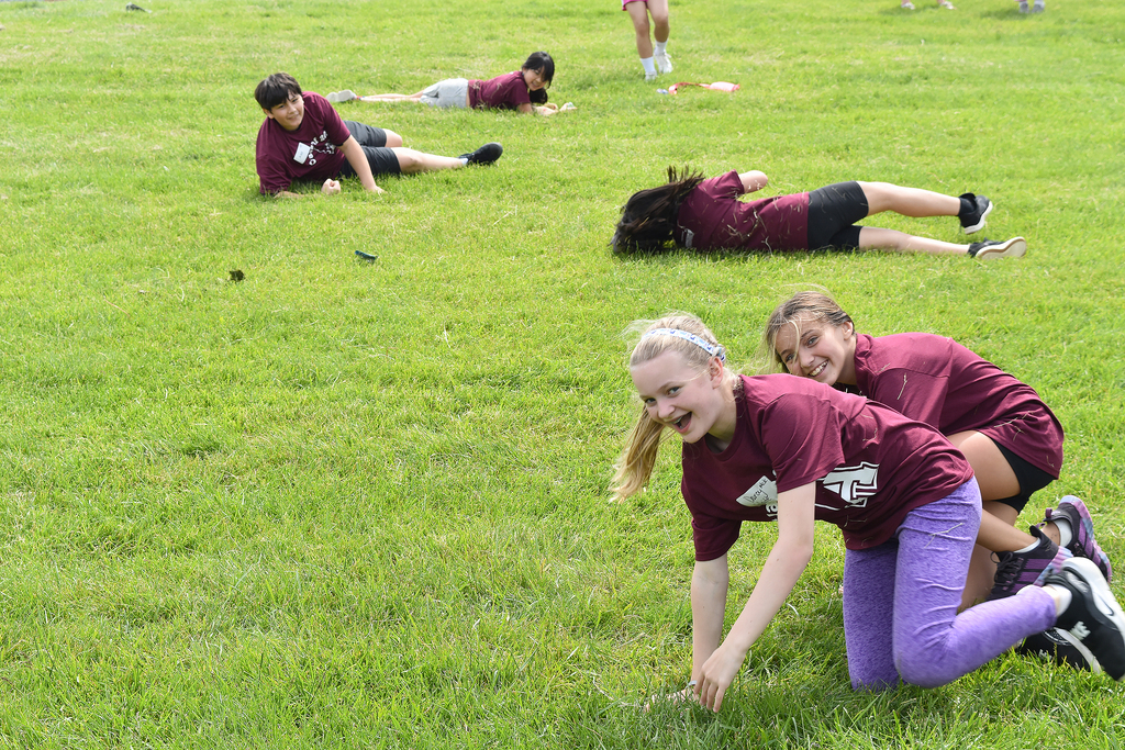 5th graders enjoy rolling down a hill of green grass
