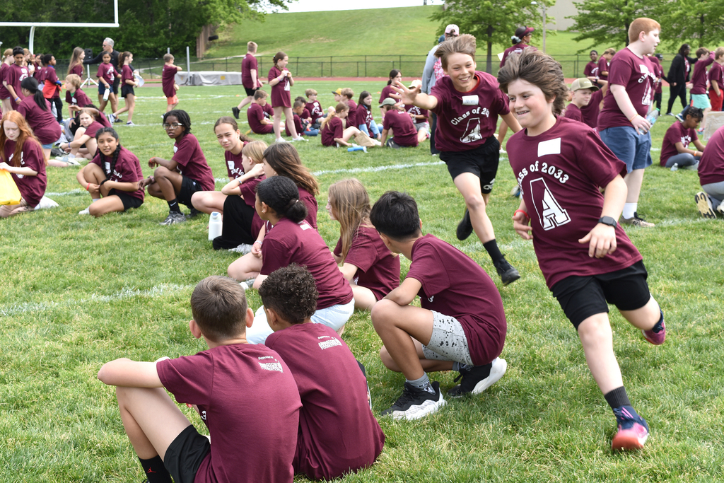 Students sit in circles and chase one another in a game of  Duck, Duck, Goose