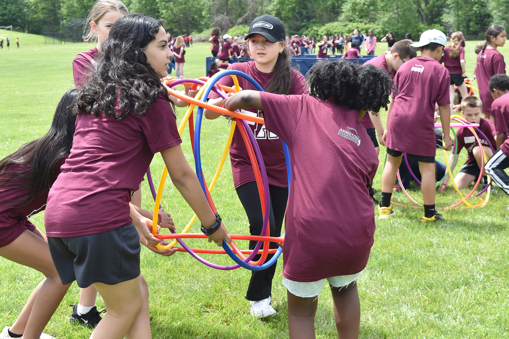 Students carry a group of colorful hula hoops during a team-building game