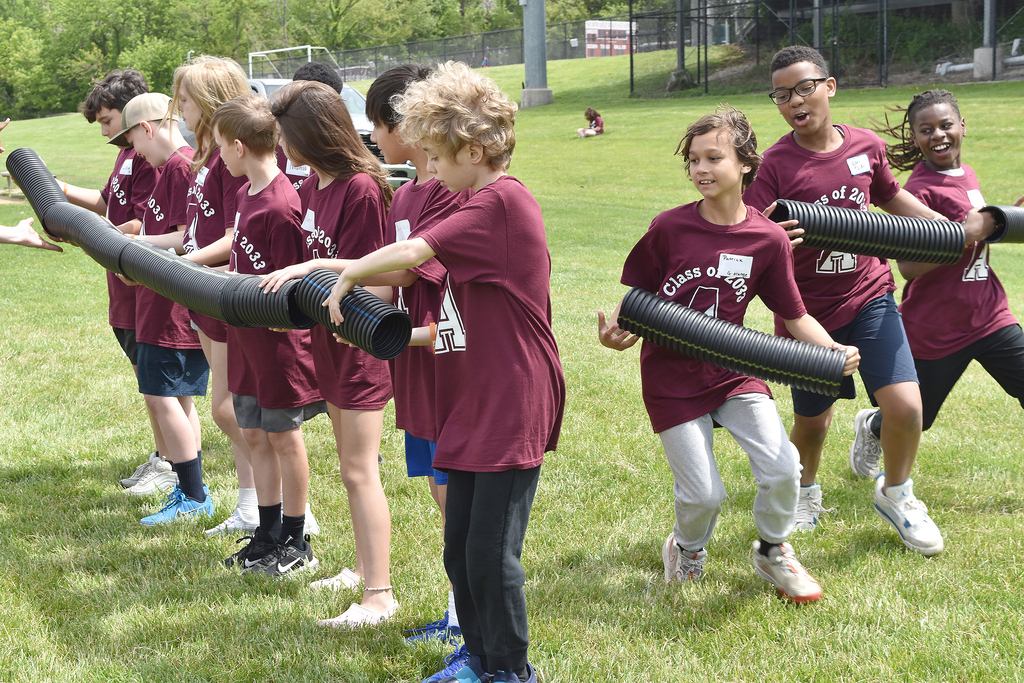 Students run to connect black piping in a team-building activity