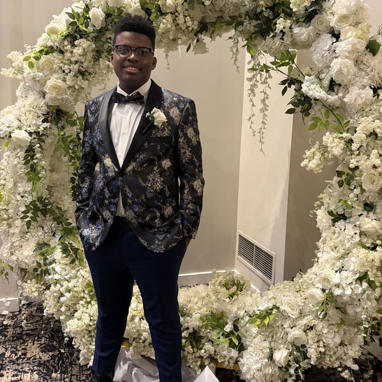 Student in a floral suit jacket in front of a floral backdrop