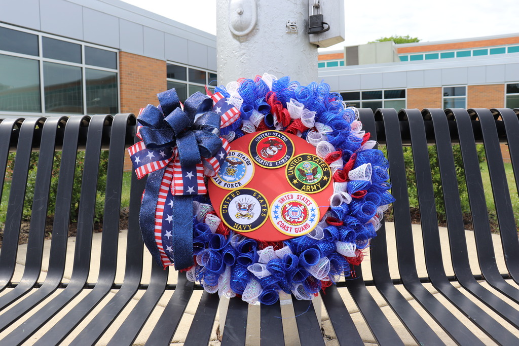 The Memorial Day wreath sits on an empty bench in front of the flagpole