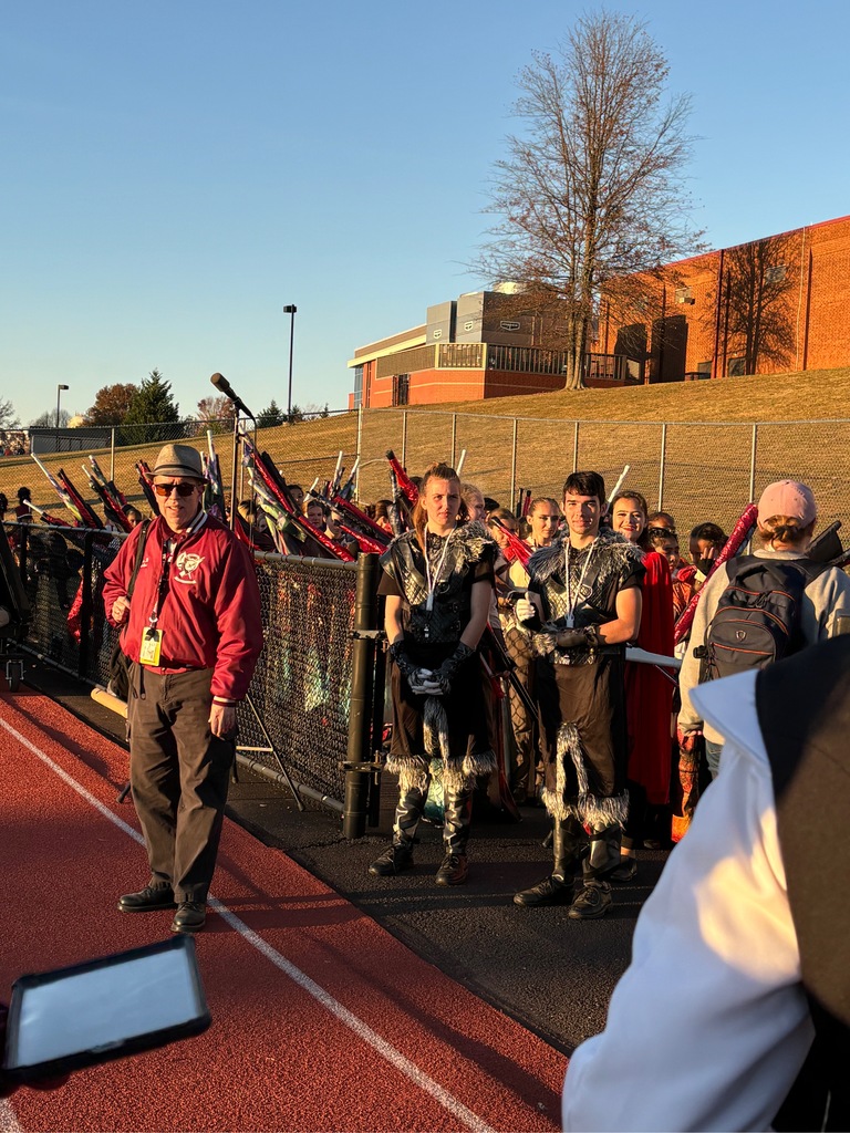 Mr. Detato walking alongside the ASHS Marching Band drummajors of 2024