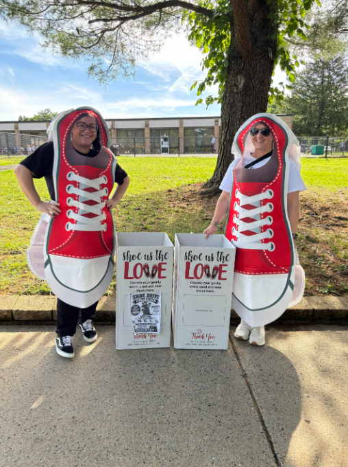 Two parent volunteers wearing shoe outfits waiting for shoe donations.