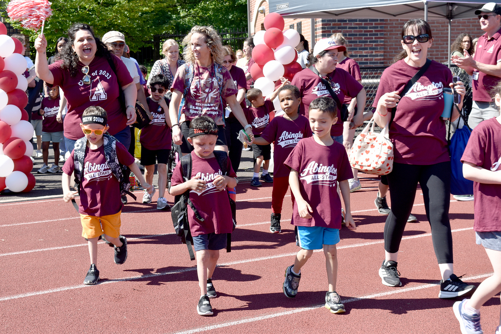 Students and staff cheer and wave pom poms while they enter Schwarzman stadium