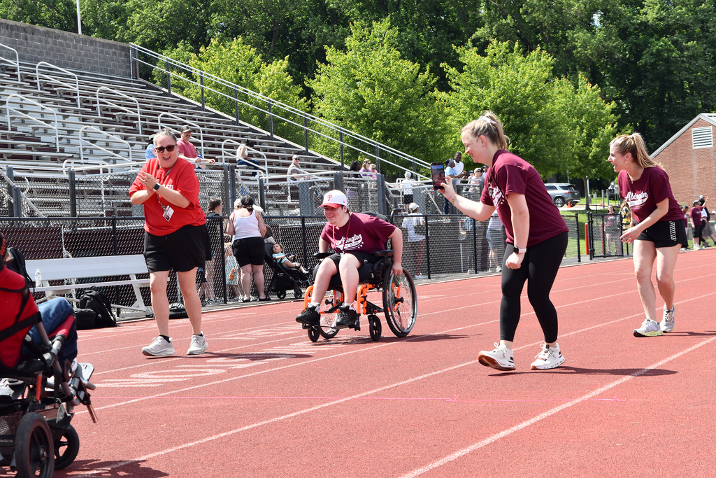 A student approaches the finish line in the wheelchair race being cheered on by staff members