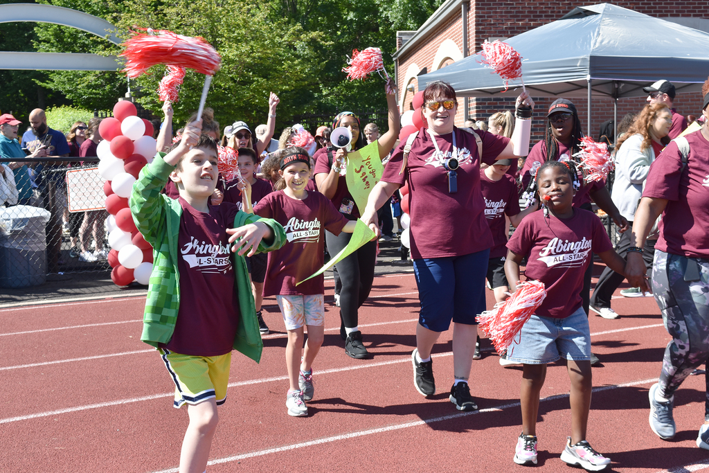 Students and staff cheer and wave pom poms while they enter Schwarzman stadium