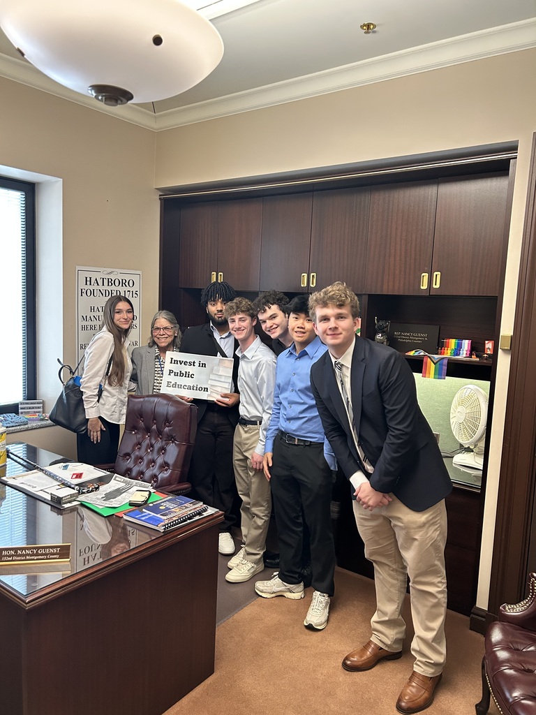 Students pose with Rep. Nancy Guenst in her Capitol office, holding an "Invest in Public Schools" sign