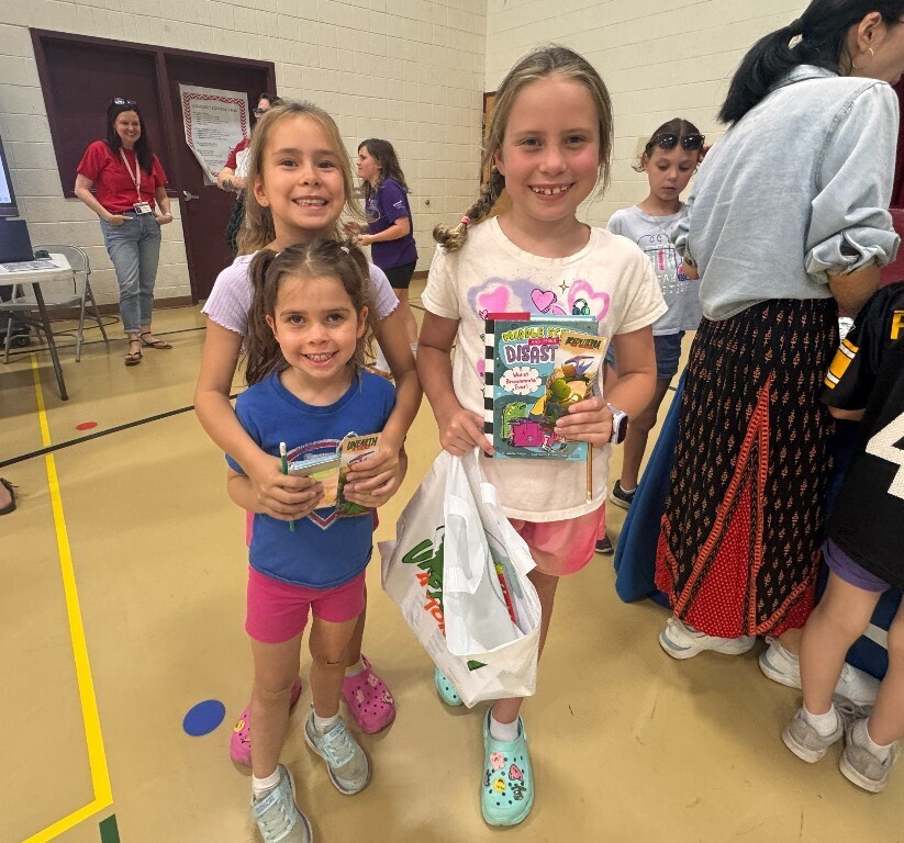 Three Overlook students smile as they hold the resources they received at the fair.