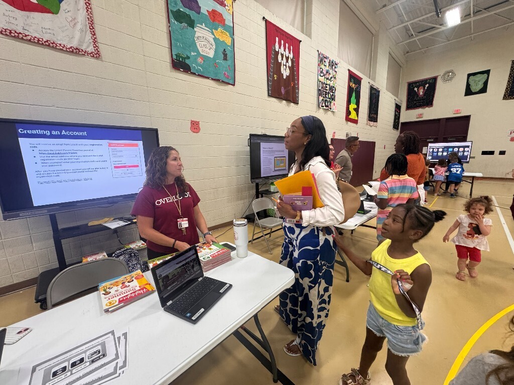 An Overlook teacher provides information to a family and student about summer resources.